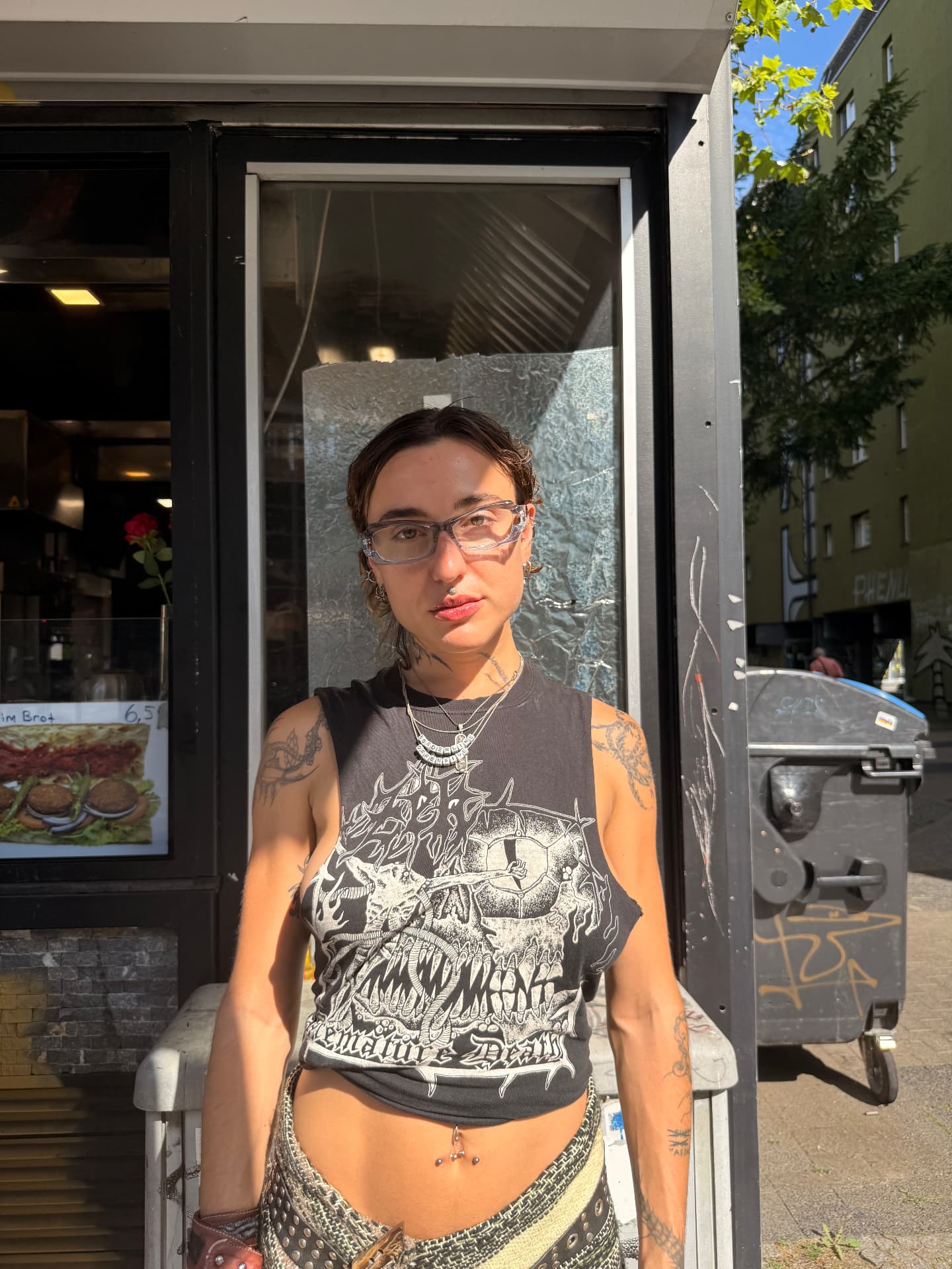 Member with glasses and layered necklaces standing in front of a kiosk