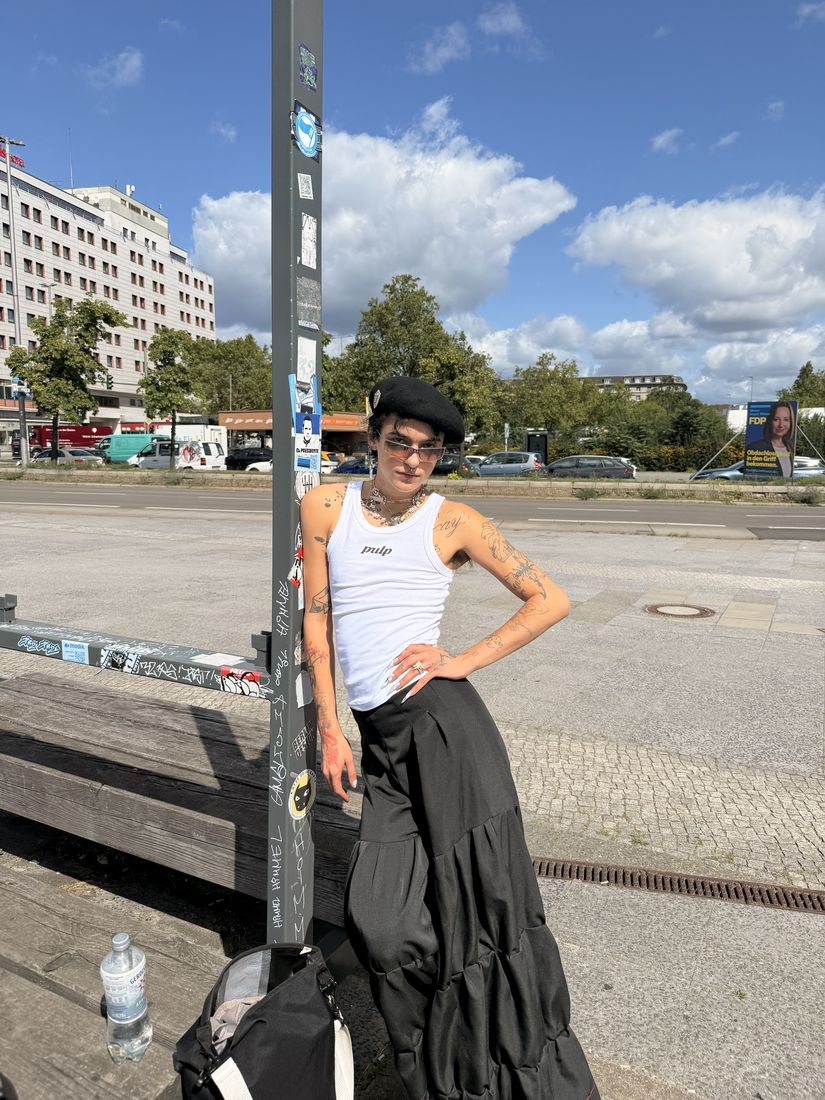 Member in a Pulp tank top and black beret leaning on a street pole