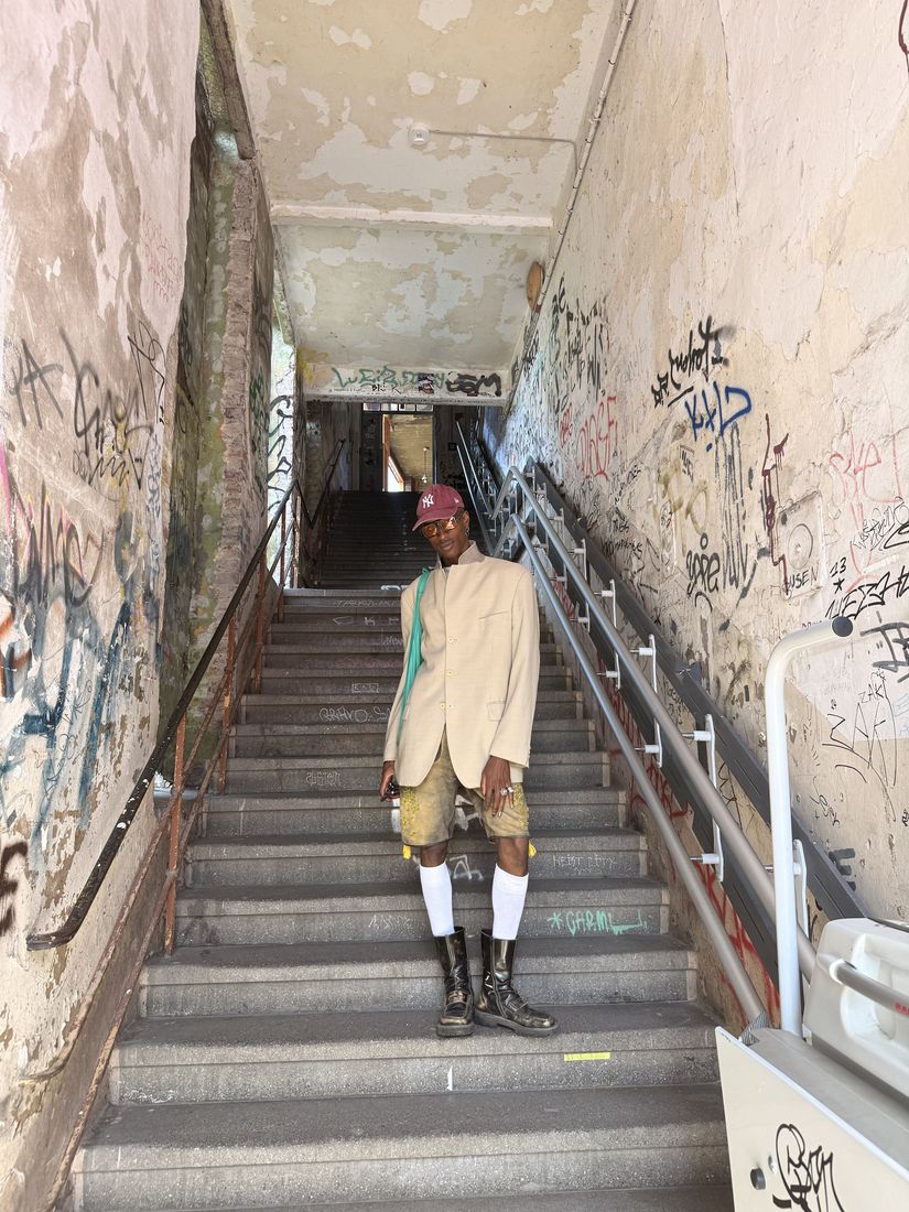Member in a beige blazer on a graffiti-covered staircase